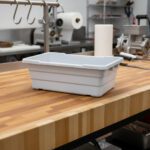A white plastic lug sitting on a butcher shop counter