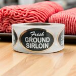 Fresh Ground sirloin Foil Sticker on a roll of labels with ground sirloin in the background