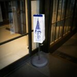 Small wet umbrella bag on a rack outside a hotel lobby