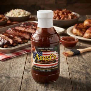 Angi's Barbecue Sauce on a table with BBQ dishes behind it