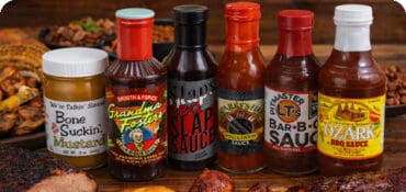 Barbecue Sauces bottles shown with bbq meats on table