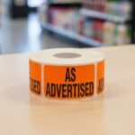 As Advertised sticker on a rectangle orange label with black text