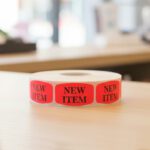 new item sticker on a red label with black text