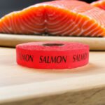 salmon sticker on a red label with black text