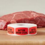 bottom round steak sticker on a red label with black print