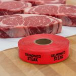 delmonico steak sticker on a red label with black print