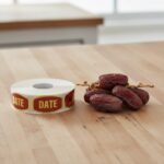 date sticker on a gold foil labels shown with several date fruits