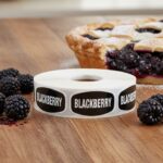 blackberry sticker with black background and white text with blackberry pie next to the roll of labels